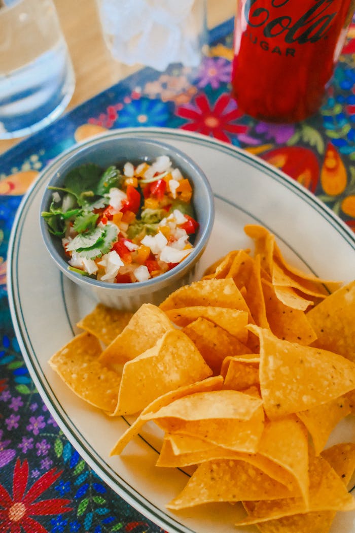A plate of nachos with salsa on a colorful table setting, perfect for a fiesta.